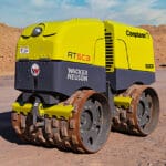 Yellow and gray Wacker Neuson Smooth Drum Roller on a dirt construction site.