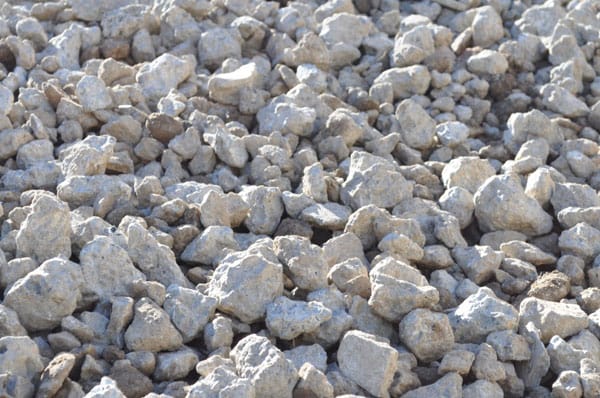 A close-up view of a pile of light gray, irregularly shaped rocks and stones showcases the rugged and uneven surface. This intricate detail and texture exemplify emerging practices in sustainable building, highlighting nature's raw materials in their unrefined beauty.