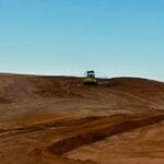 431432780_856162846523039_7751113895643703576_n - Conplant Pty Ltd A bulldozer works on a barren, sandy hill under a clear blue sky.