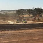 431751892_920115986418002_1087214421264581898_n - Conplant Pty Ltd Dusty construction site with two road rollers compacting soil and an orange excavator moving dirt, trees in the background.