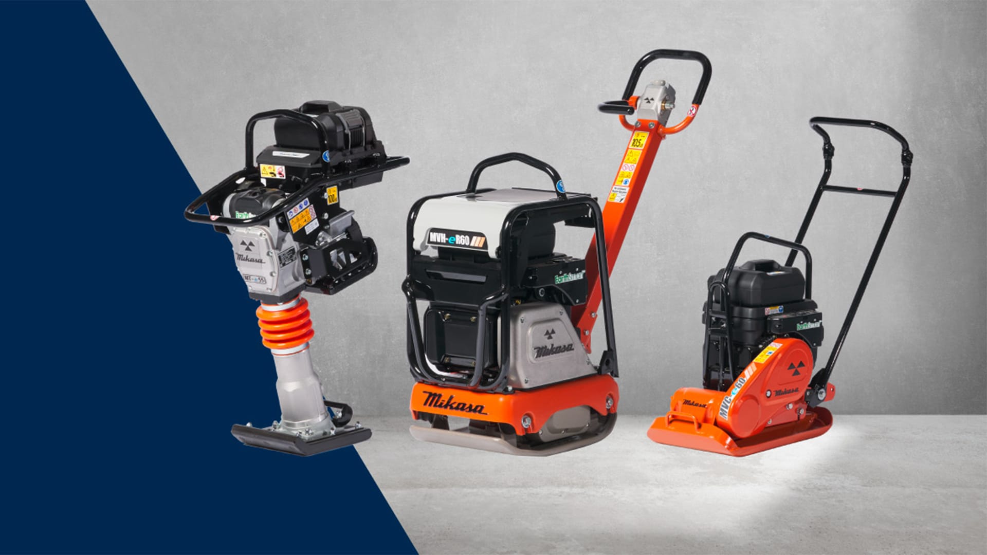 Three construction tools displayed: a vibratory rammer with a yellow and red spring, a vibratory roller in black and orange, and a plate compactor with a black base and orange handle, all positioned on a gray floor with a textured wall backdrop.