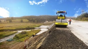 Remote Unmanned - Conplant Pty Ltd An autonomous road roller compacts asphalt on a highway under construction, with workers nearby.