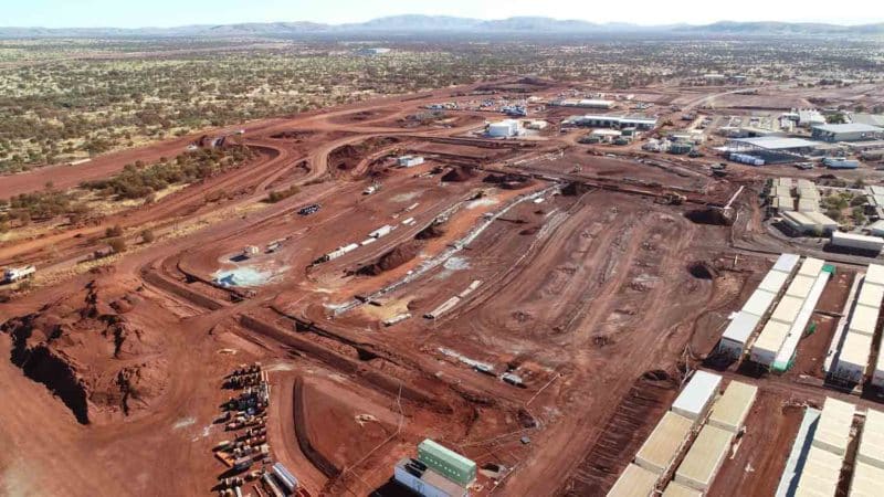 Aerial view of a large mining site with red soil, equipment, and buildings.