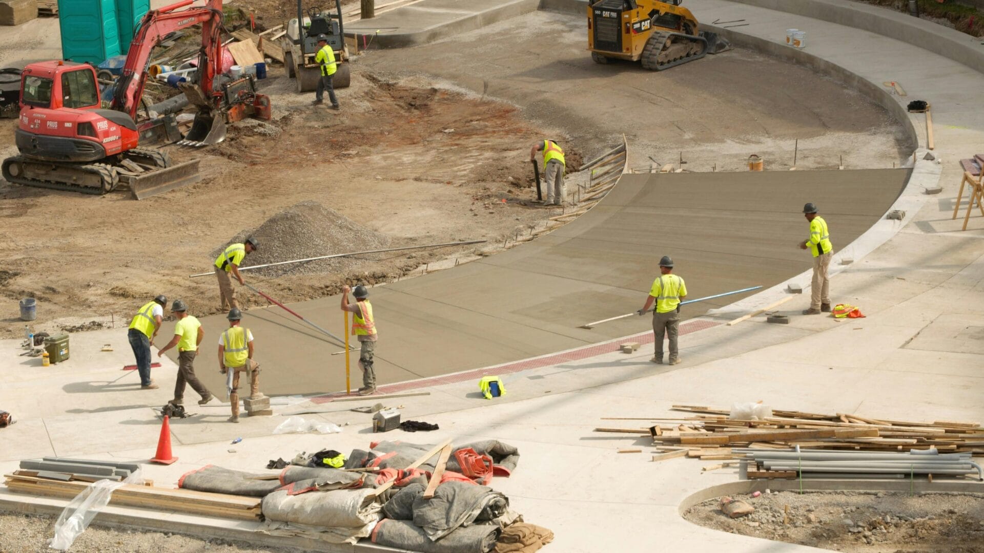 Workers in yellow vests smooth fresh concrete, showcasing civil construction trends for 2026.