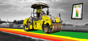 Yellow road roller on a construction site paving a multicolored lane (red, orange, yellow, green) with a floating tablet showing a color-coded pavement chart, left-to-right scenery in grayscale.